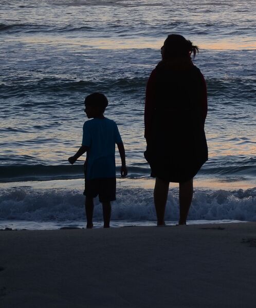 Mutter und Sohn von hinten an einem Sandstrand